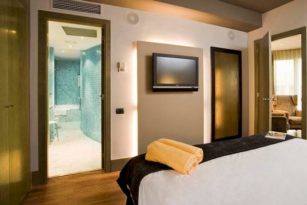 Innenansicht eines Zimmers im Gran Hotel Havana Barcelona mit Bett, Fernseher und offenem Badezimmer