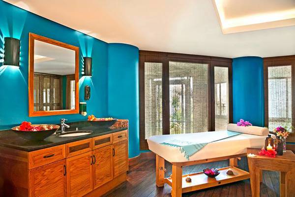 Wellnessbereich im Kempinski Hotel Barbaros Bay Bodrum mit blauen Wänden, einer Massageliege und einem Waschbecken.
