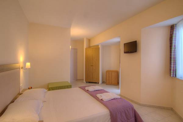 Ein geräumiges Hotelzimmer im Solimar Dias Hotel mit einem Bett, Kissen, Decken, einem Fernseher und einem Kleiderschrank.