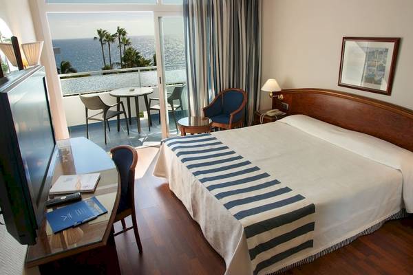 Vik Hotel San Antonio Zimmer mit Balkon und Meerblick, Bett, Fernseher, Schreibtisch und Tisch mit Stühlen.