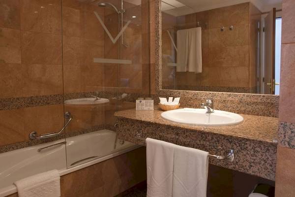 Badezimmer im VIK Hotel San Antonio mit Badewanne, Waschbecken und Spiegel.