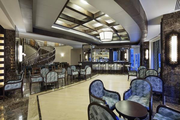 Innenansicht der Lobby des Liberty Hotels Lara mit Bar, Sitzbereich und Wendeltreppe.