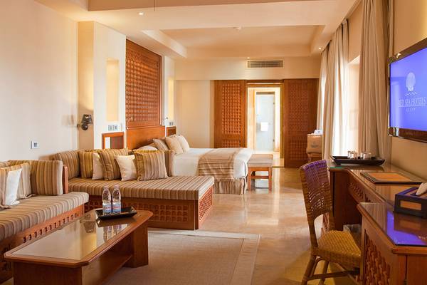 Innenansicht der Suite im Grand Waterworld Makadi Hotel mit Doppelbett, Wohnzimmer und Fernseher.