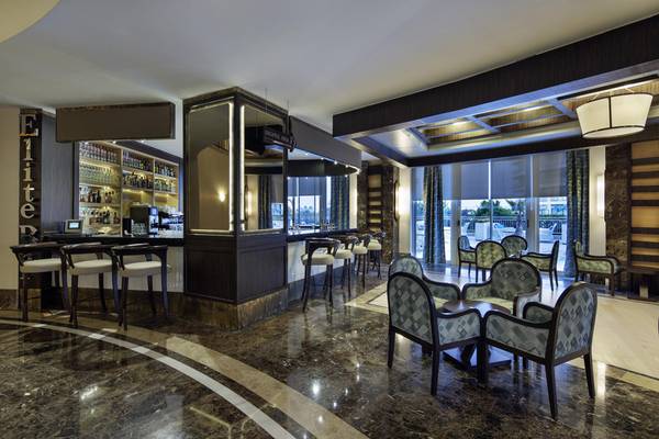 Barbereich im Liberty Hotels Lara mit Marmorboden und modernen Stühlen.