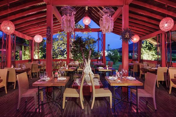 Innenansicht des Restaurants im Liberty Hotels Lara mit roten Säulen und Holzboden.