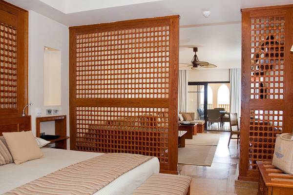 Schlafzimmer im Grand Waterworld Makadi Hotel mit Holzelementen und modernen Möbeln.