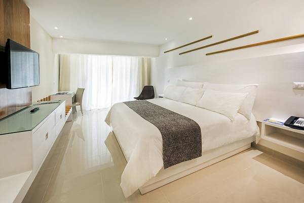 Schlafzimmer im IFA Villas Bavaro Hotel mit einem großen Bett, Fernseher und minimalistischem Design.