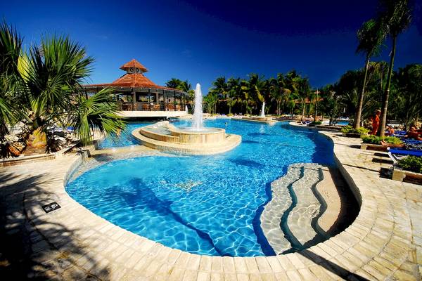 Pool im IFA Villas Bavaro Hotel mit einer Wasserfontaene und umgeben von Palmen.