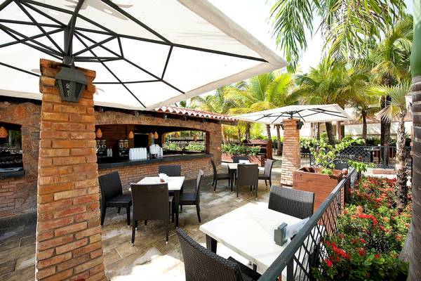 Terrasse des IFA Villas Bavaro Hotels mit Tischen, Stühlen und Sonnenschirmen.