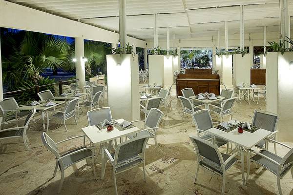 Restaurantbereich des IFA Villas Bavaro Hotel mit weißen Tischen und Stühlen und hängenden Pflanzen.