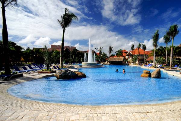 Außenbereich des IFA Villas Bavaro Hotel mit großem Swimmingpool, Palmen und Sonnenliegen.