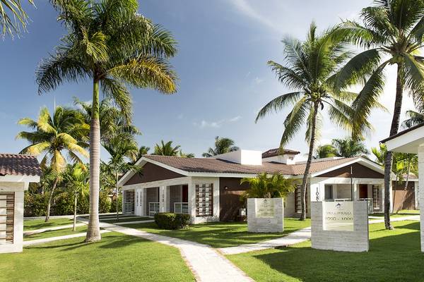 Außenansicht des IFA Villas Bavaro Hotel mit mehreren Bungalows, Palmen und gepflegtem Rasen.