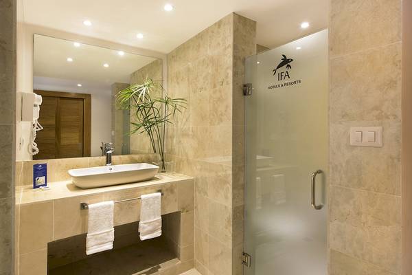 Badezimmer im IFA Villas Bavaro Hotel mit Waschbecken, Spiegel und Glastür.