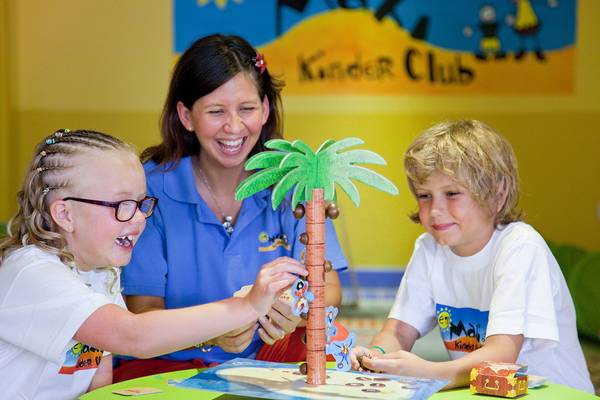 Eine Erzieherin und zwei Kinder spielen ein Spiel im Kinderclub des Grand Waterworld Makadi Hotels.