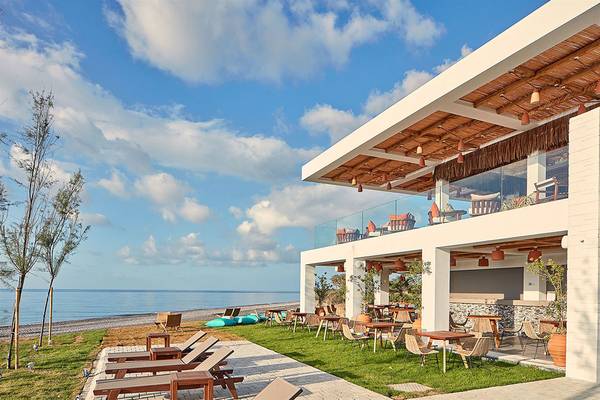 Außenbereich des Atlantica Dreams Resorts mit Blick auf das Meer und Loungeliegen.