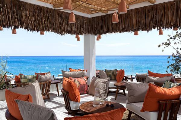 Terrasse im Atlantica Dreams Resort mit Blick auf das Meer und orange Kissen.