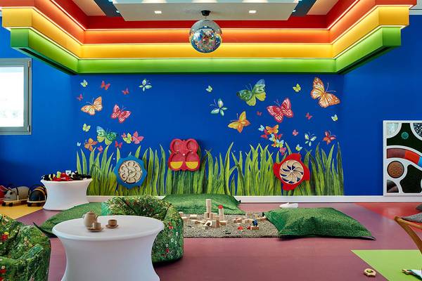 Kinderzimmer im Atlantica Dreams Resort mit blauer Wand, bunten Schmetterlingstapeten und Spielzeug.