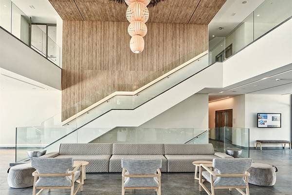 Innenansicht der Lobby des Atlantica Dreams Resort mit moderner Einrichtung, Couch, Stühlen, Tisch, Glasgeländer und Treppe.