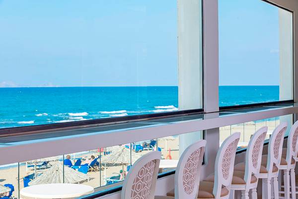 Innenblick des Civitel Creta Beach Hotel mit Blick auf den Strand, Sonnenschirmen und Stühlen.