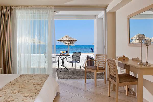 Hotelzimmer im Civitel Creta Beach mit Terrasse und Meerblick, mit Tisch, Stühlen und einem Bett.