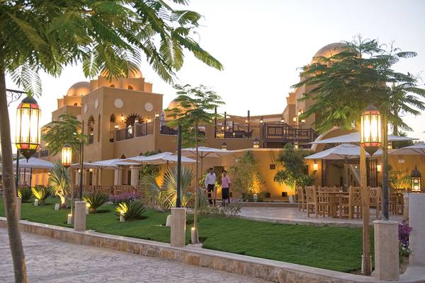 Außenbereich des Grand Waterworld Makadi Hotels mit Terrasse, Tischen und Stühle sowie Beleuchtung