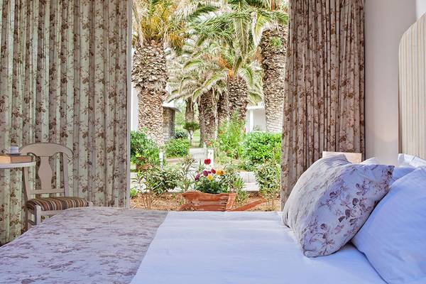 Hotelzimmer im Civitel Creta Beach mit Blick auf einen Garten und Palmen.