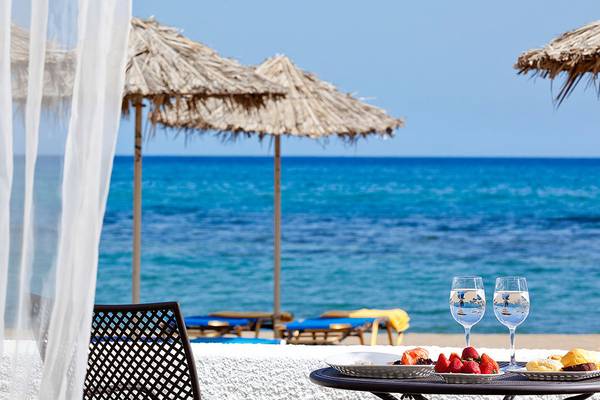 Ausblick vom Hotelzimmer des Civitel Creta Beach auf die Strandszene mit Schirmen, Tisch und Meer.