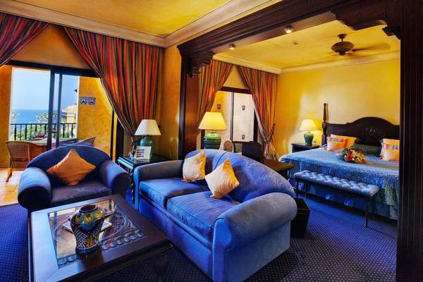 Innenansicht eines Hotelzimmers der Europe Villa Cortes mit gelben Wänden, blauem Sofa und Aussicht auf das Meer.