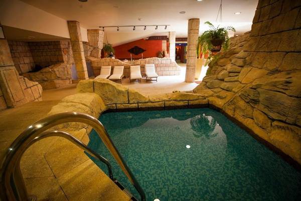 Innenpool des Hotels Europe Villa Cortes mit Liegestühlen und Steinwänden.