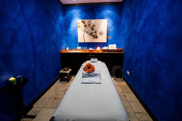 Massageraum im Hotel Europe Villa Cortes mit blauen Wänden, einem Behandlungstisch und Dekoration.