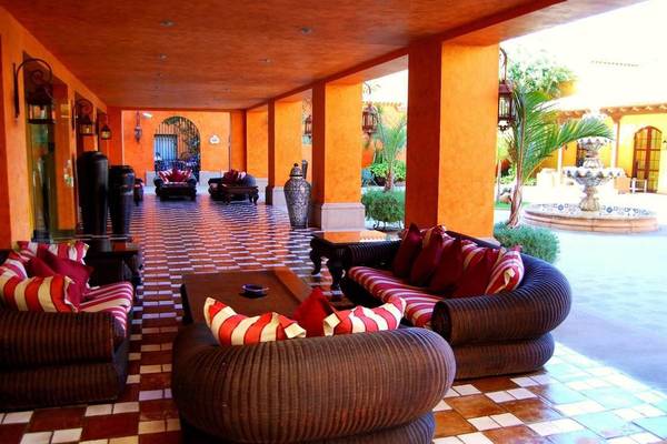 Lounge-Bereich des Hotel Villa Cortes mit orangefarbenen Wänden und gemusterten Bodenfliesen.