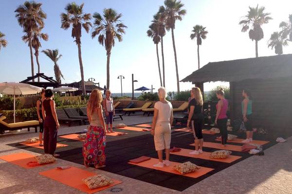 Yogakurs im Freien im Europa Villa Cortes mit Teilnehmern und Palmen im Hintergrund.
