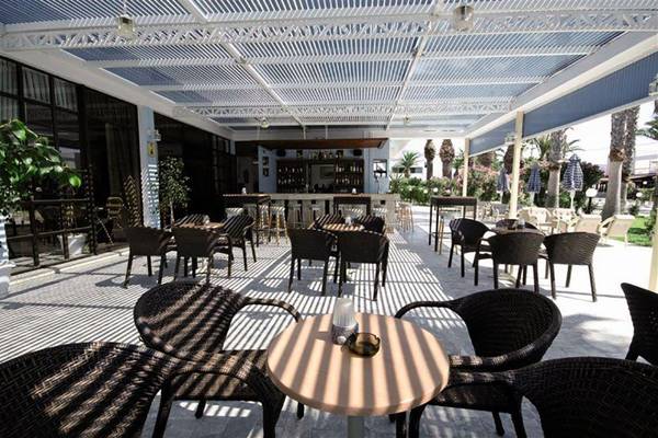 Außenterrasse des Tropical Sol Hotels mit Tischen, Stühlen und Schattenbereichen.
