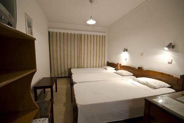 Drei Betten im Zimmer des Tropical Sol Hotels, alle mit weißen Laken bezogen.