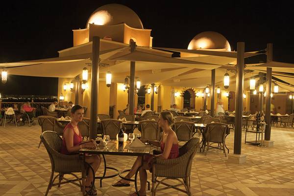Außenterrasse des Grand Waterworld Makadi Hotels bei Nacht mit beleuchteten Pavillons und Gästen.