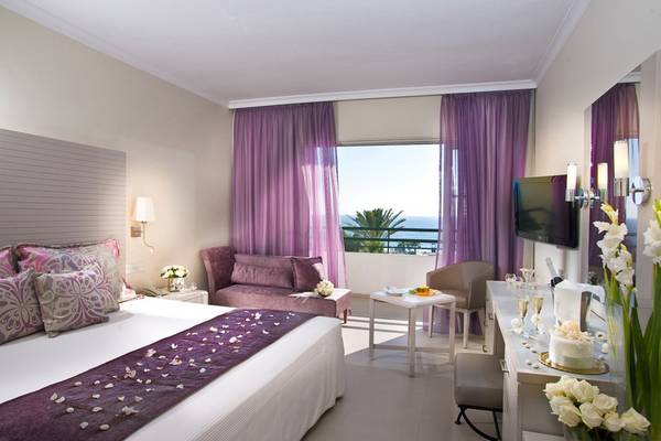 Innenansicht eines Hotelzimmers im Louis Imperial Beach Hotel mit Bett, Sofa und Aussicht auf das Meer.