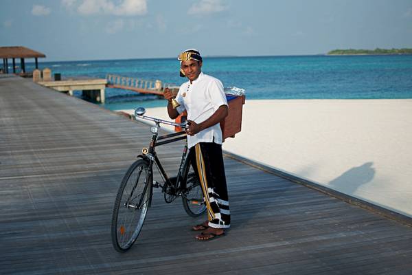Mitarbeiter des Noku Maldives mit Fahrrad auf Strand