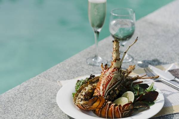 Gegrillter Hummer auf einem Teller mit Salat und Limetten auf einer Poolseite im Noku Maldives