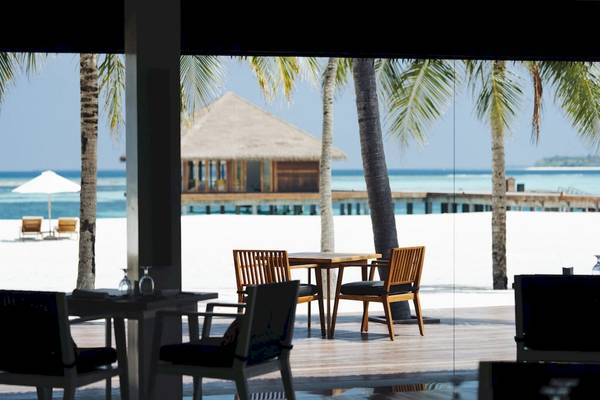 Innenansicht des Noku Maldives Restaurants mit Ausblick auf das Meer und eine überdachte Terrasse.