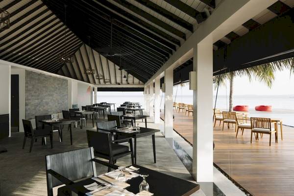Innenbereich des Restaurants im Noku Maldives Hotel mit modernen Möbeln und Blick auf den Ozean.