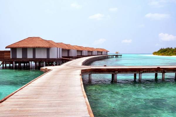 Reihe von Wasserbungalows im Noku Maldives mit Gehweg über das Wasser