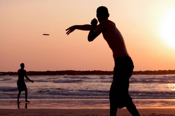 Silhouette von zwei Männern, die Frisbee am Strand spielen