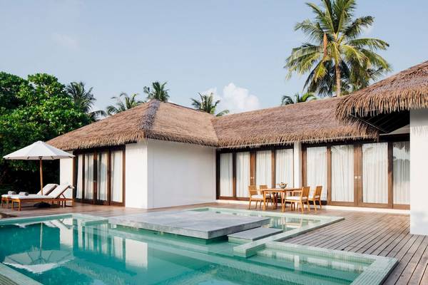 Außenbereich der Noku Maldives Villa mit Pool, Lounge-Liegen und Tisch im Freien.