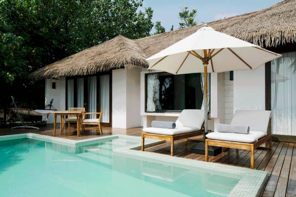 Villa im Noku Maldives mit Swimmingpool, Sonnenliegen und Sonnenschirm