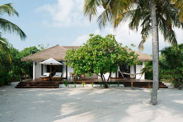 Noku Maldives Strandhaus mit Dach, Lounge-Sesseln und Sonnenschirm