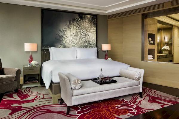 Schlafzimmer im Sofitel Bangkok Sukhumvit Hotel mit großem Bett, zwei Nachttischen und einem großen Wandgemälde.