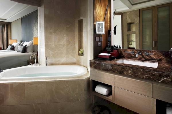 Badezimmer im Sofitel Bangkok Sukhumvit mit Badewanne, Waschbecken und Spiegel.