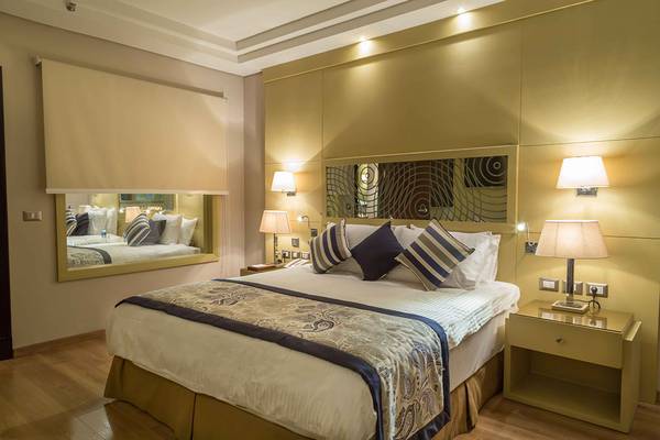 Hotelzimmer im Rixos Premium Seagate mit großem Bett, Nachttischen und Spiegel.