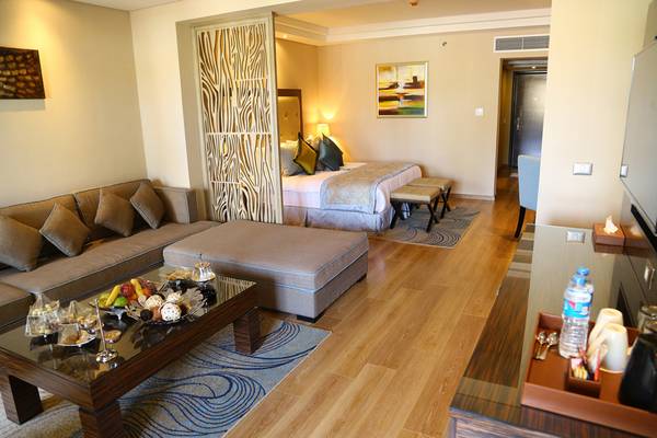 Suite-Zimmer im Rixos Premium Seagate mit Doppelbett, Sofa, Couchtisch und Frühstücksauswahl.