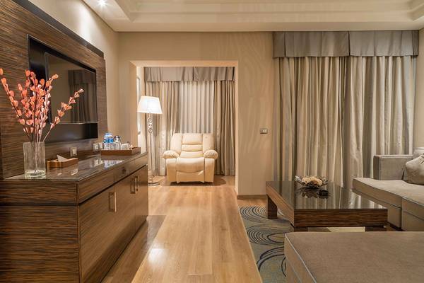 Modernes Hotelzimmer im Rixos Premium Seagate mit Fernseher, Schrank, Sessel und Tisch.